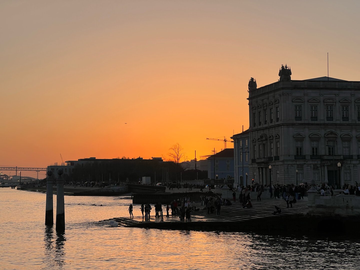 Old Portugiese buildings at shore by sunset with a red sky in the background.