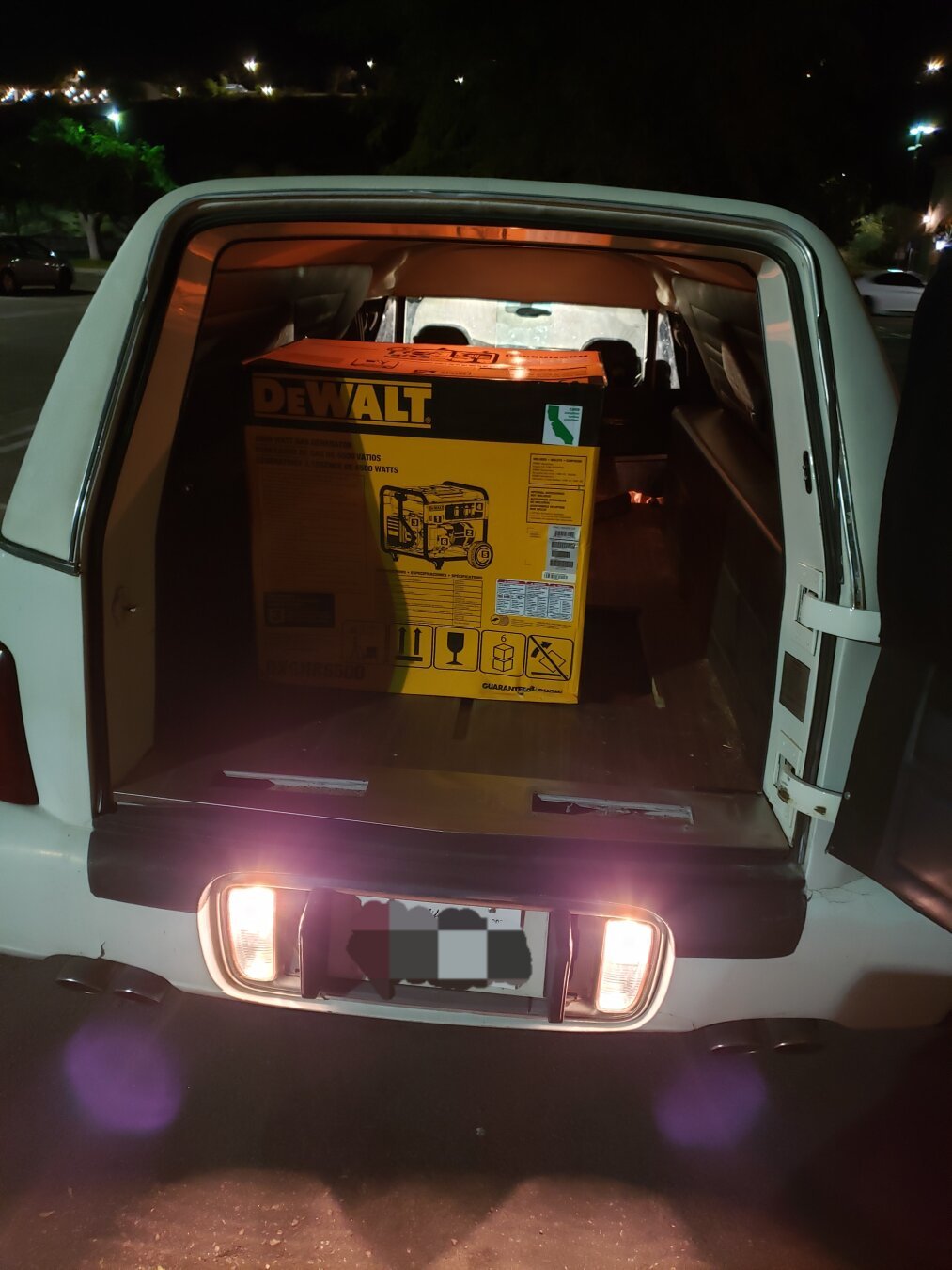 A generator loaded in the empty rear of a white 2001 Cadillac Deville Hearse