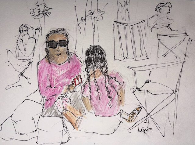 This is an urban sketch of a mother and daughter enjoying a game of cards while sitting on the lawn waiting for the concert to begin.