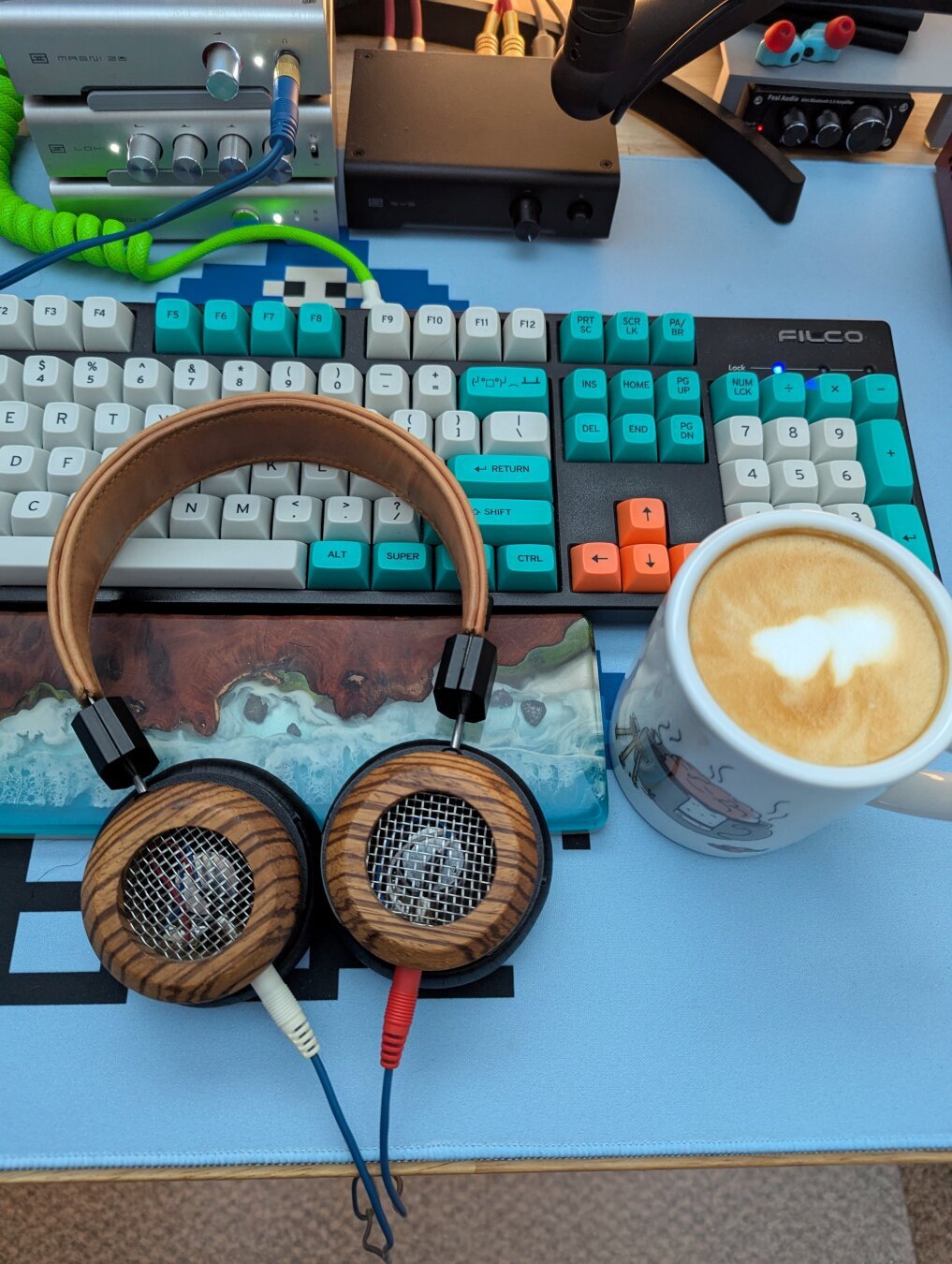 Heavily modified Grado SR80e Headphones next to a latte in front of a keyboard and blue desk mat.