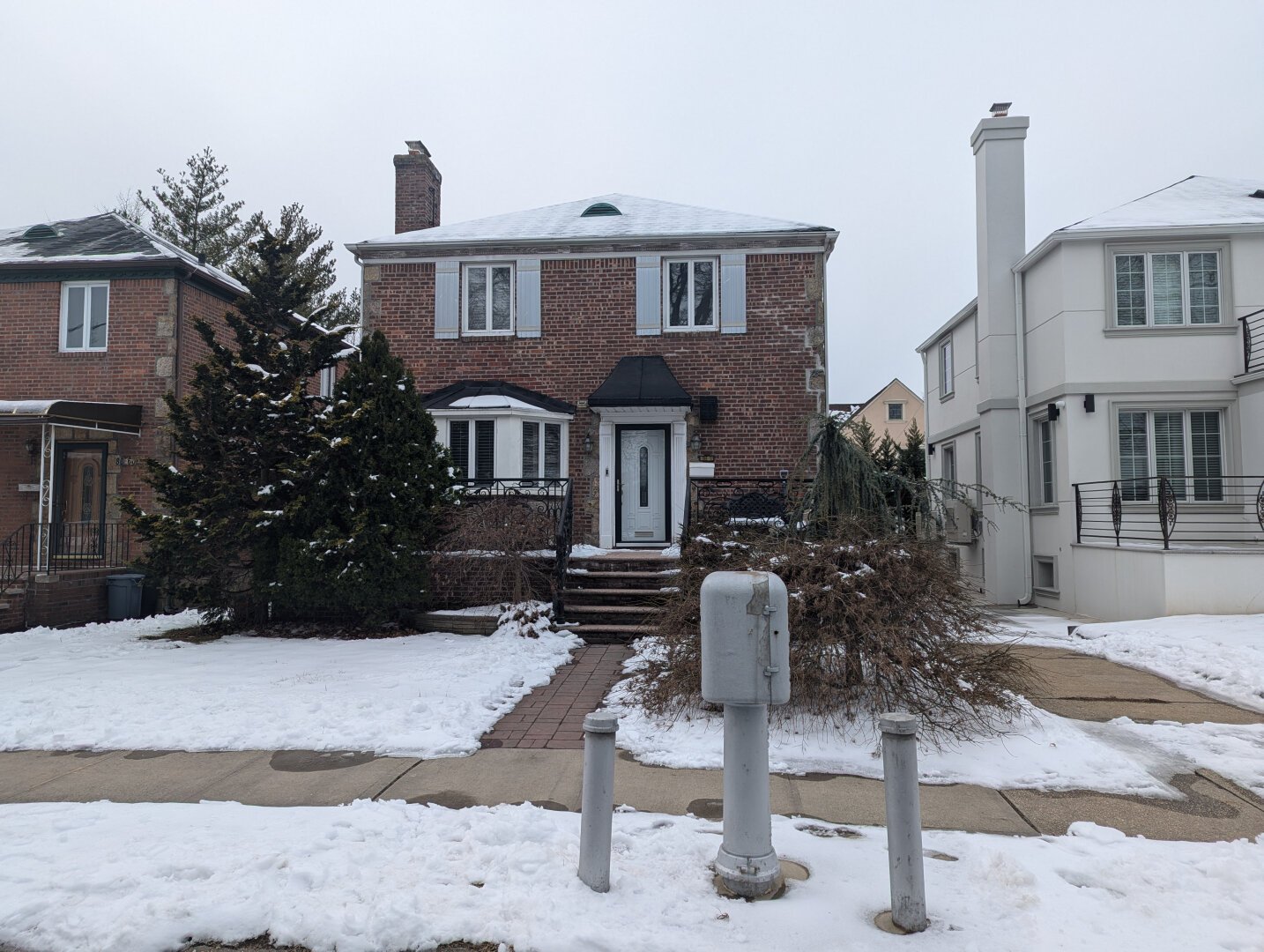 Water monitoring station seen in front of a brick house. Snow can be seen on the ground.