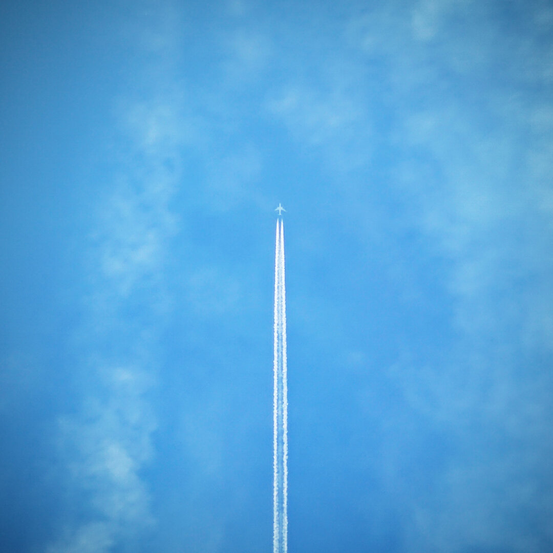 Un avion dans le ciel, laissant derrière lui des traînées de condensation.