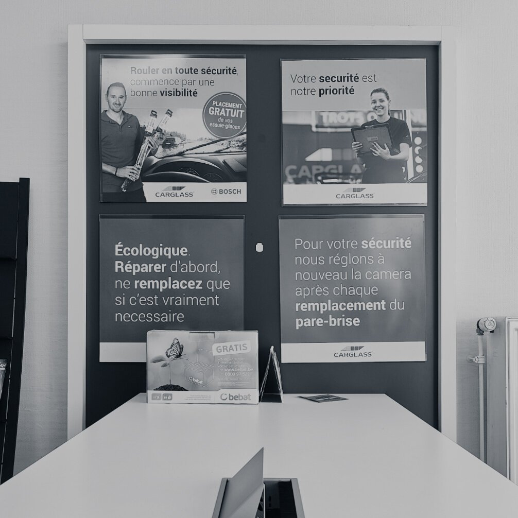 Cette image montre un espace intérieur, probablement un bureau ou une salle d'attente, avec plusieurs affiches publicitaires accrochées au mur.