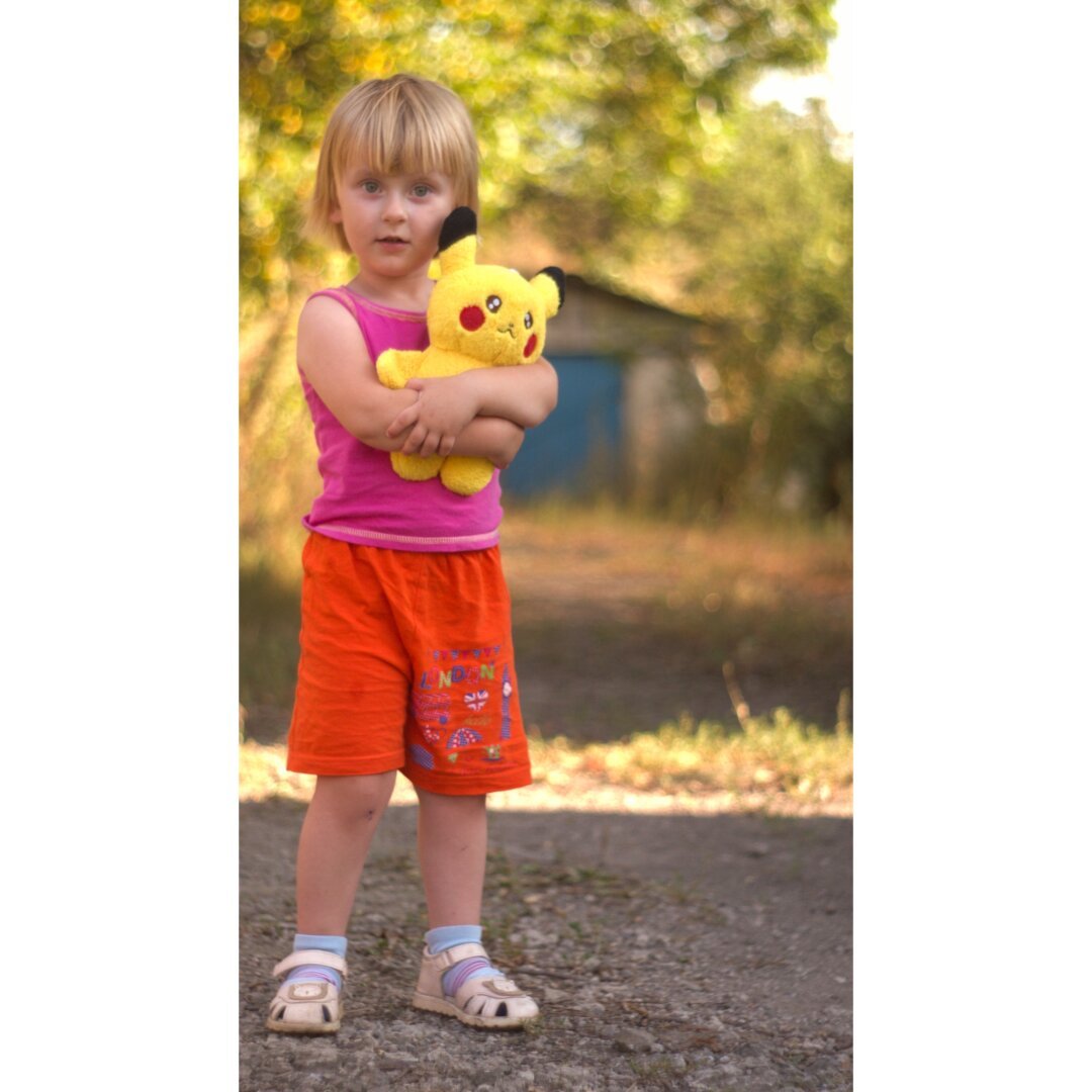 Девочка обнимает мягкую игрушку Пикачу.