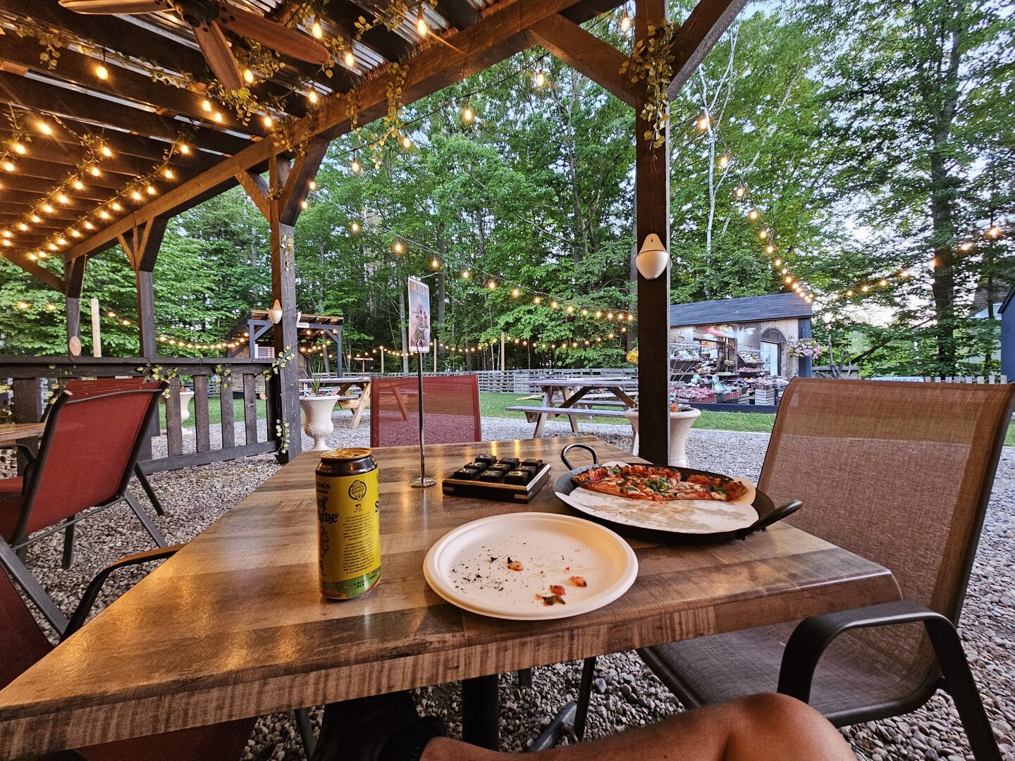 View from sitting under an awning at a pizza place with a can of beer and half a pizza on the table