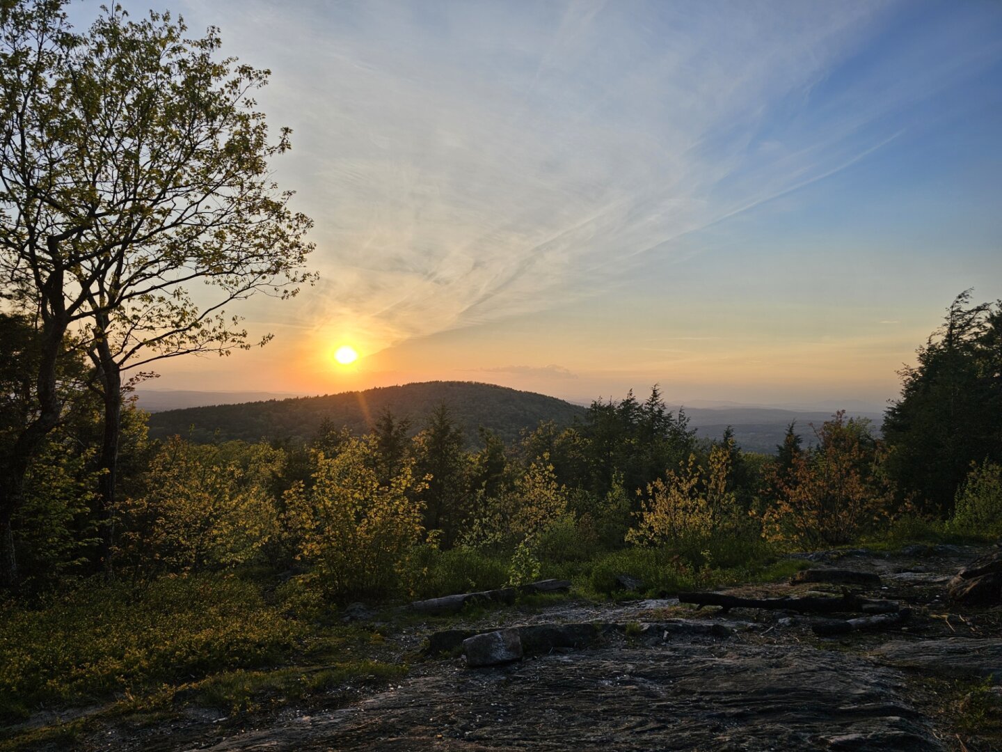 Orange sun setting over a hill with a hazy city in the back