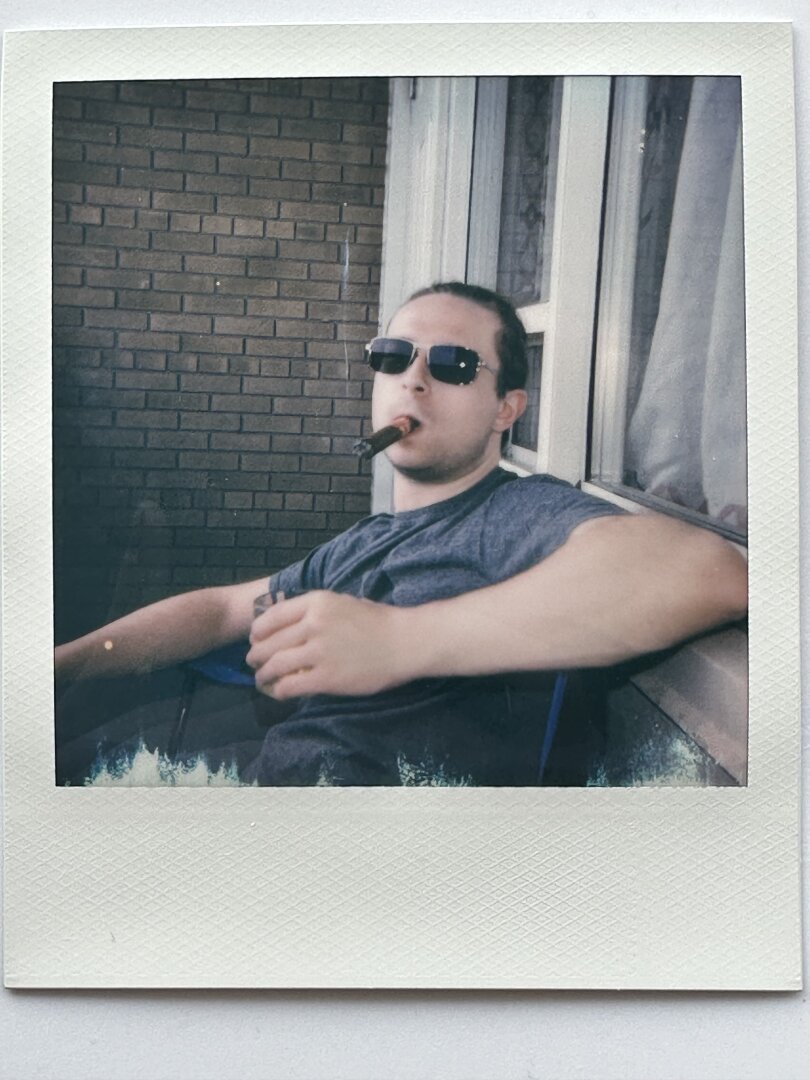 a man in sunglasses with a cigar and scotch