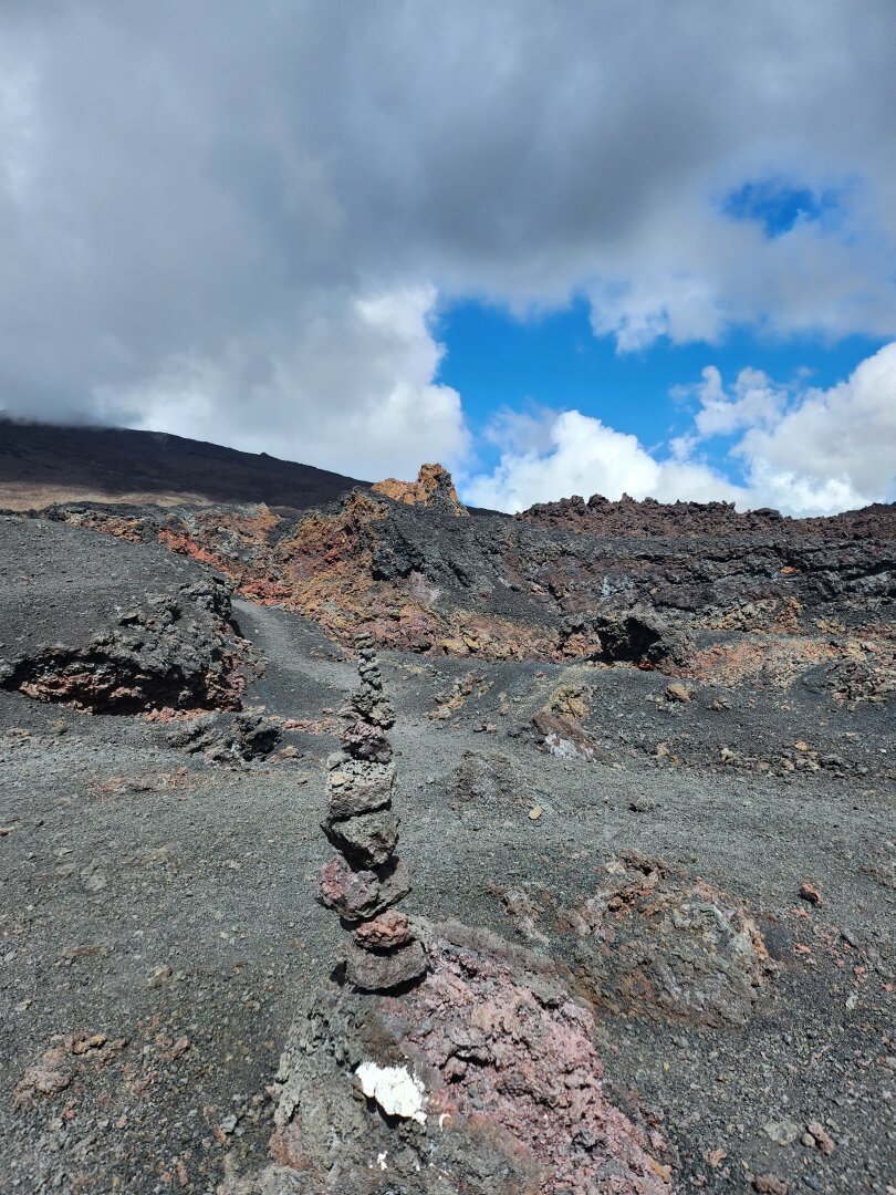 A high pile of volcanic pebbles in a rocky Martian landscape, with black and orange hues