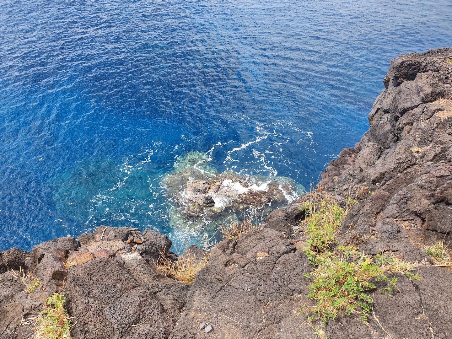 une vue plongeante dans le bleu de l'océan, avec un rocher immergé dans l'eau