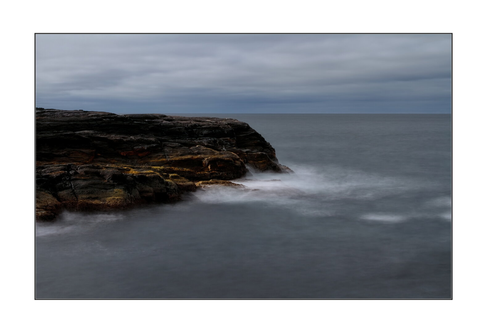 Long exposure photo of rock surrounded by the ocean.
