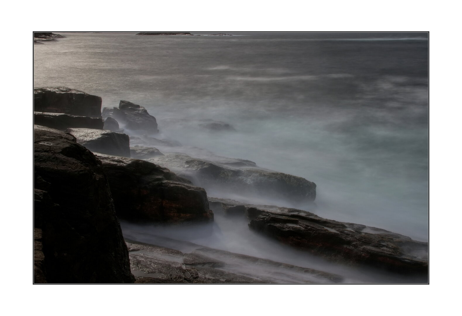 Long exposure photo of waves on the rocks.