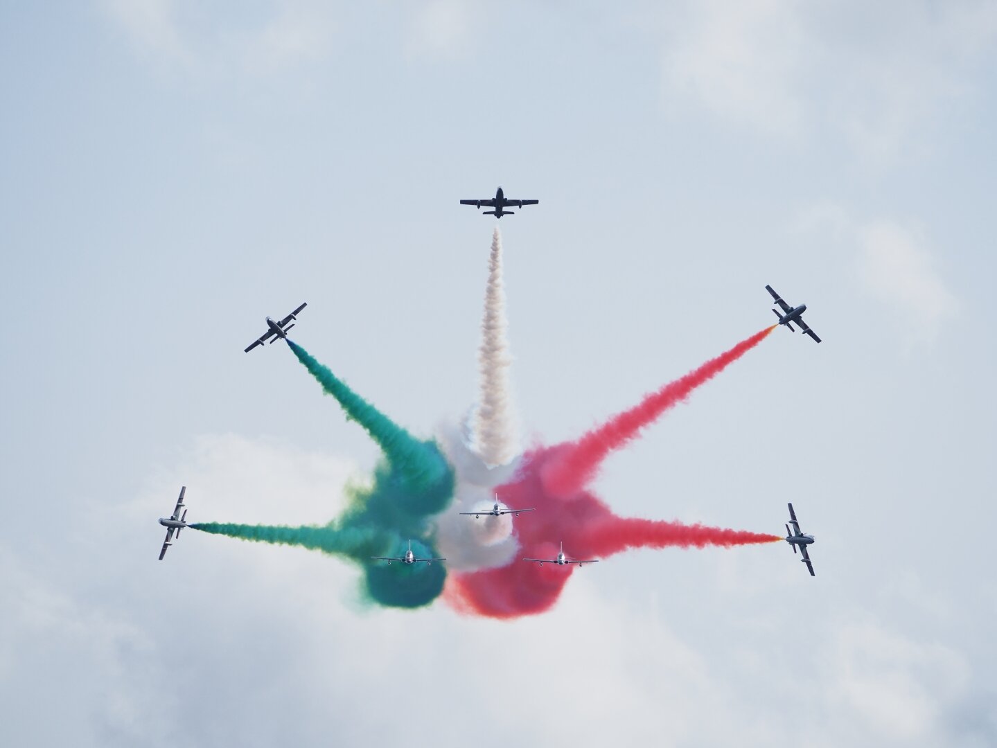Eight Italian Frecce Tricolori aircraft performing a break maneuver