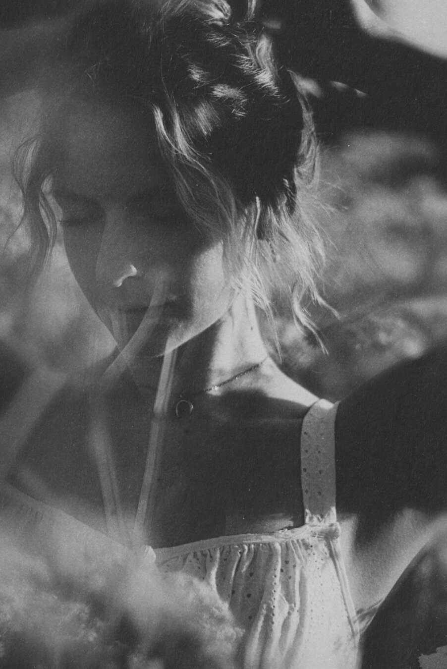 Grayscale photo of a woman fixing her hair on sunny summer evening.