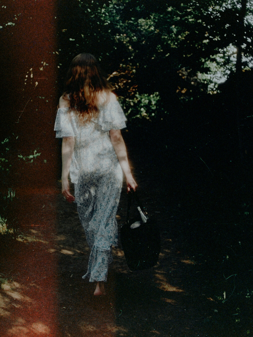 Photo of a woman in white summer dress walking away.