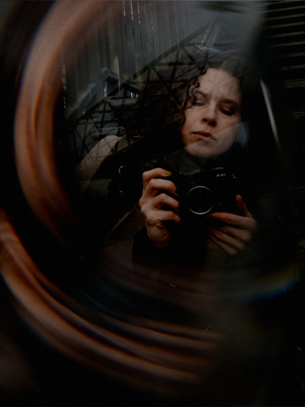 Portrait of a woman with Fujifilm camera with analogue lens swirl effect.