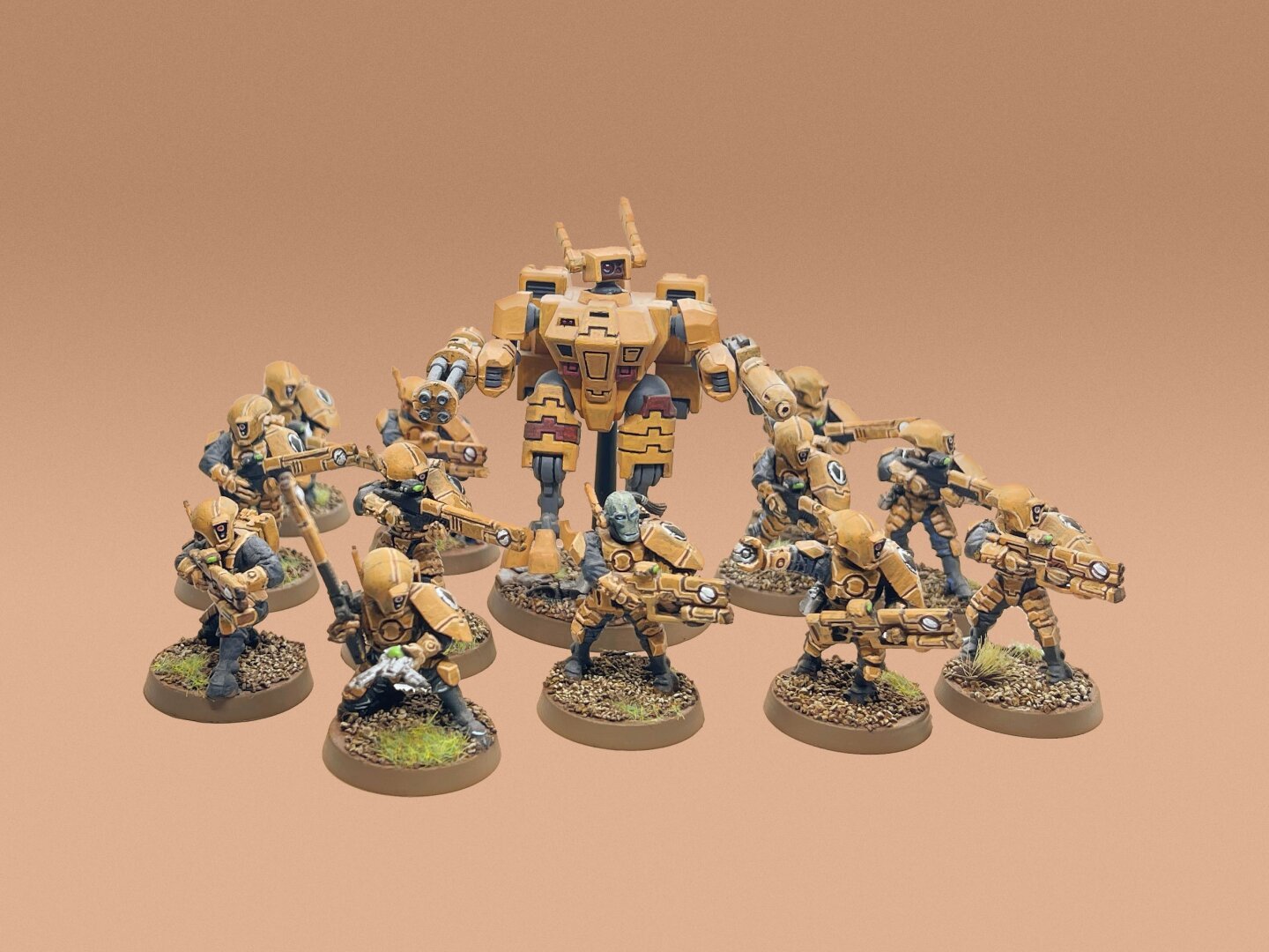 Squad of Tau infantry and Crisis Battlesuit, painted in tan colors, on a tan gradient background