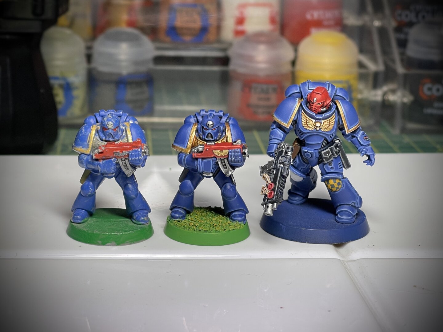 Three painted space marines, two early 90s models and one modern Primaris marine, painted to old and new standards.