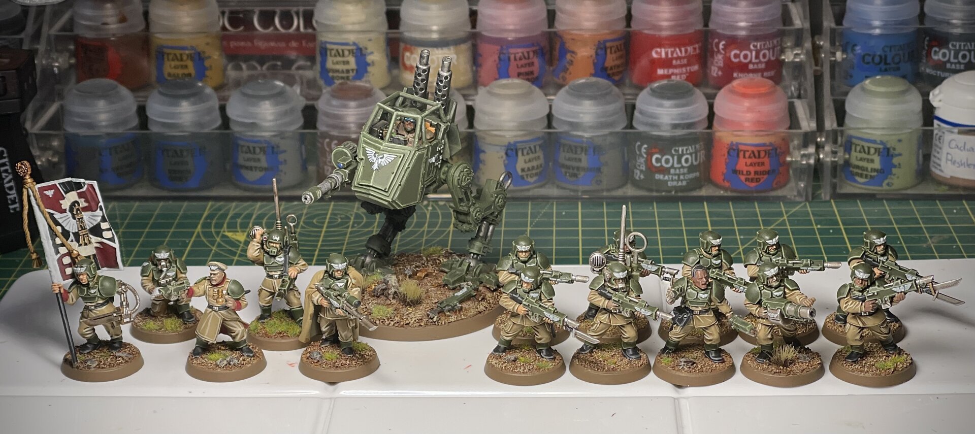 Painted WH40K Cadian force, box art style — command squad, infantry squad, and sentinel walker