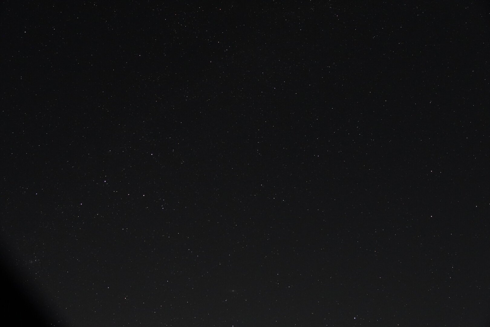 A picture of a night sky full of stars. Cassiopeia is almost lost amongst the other, dimmer stars on the left. The Andromeda galaxy can be seen as a small smudge on the bottom of the image. The milky way is barely visible as a denser band of stars running diagonally from the left of the picture to the top.