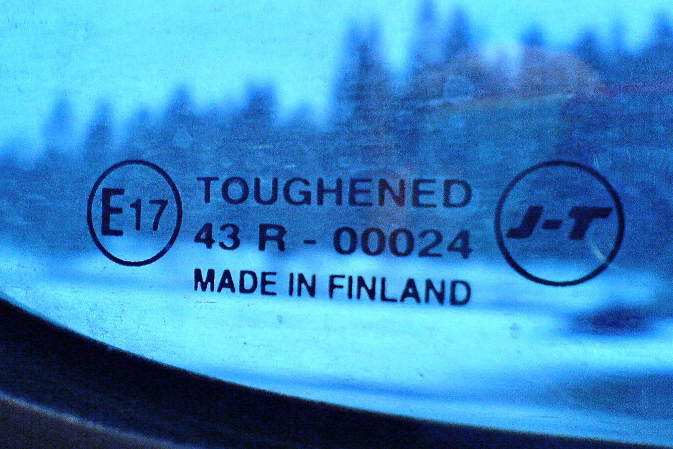 “Toughened” and “Made in Finland” imprinted in the safe glass of a train window, a wintery forest landscape blurred in the background.