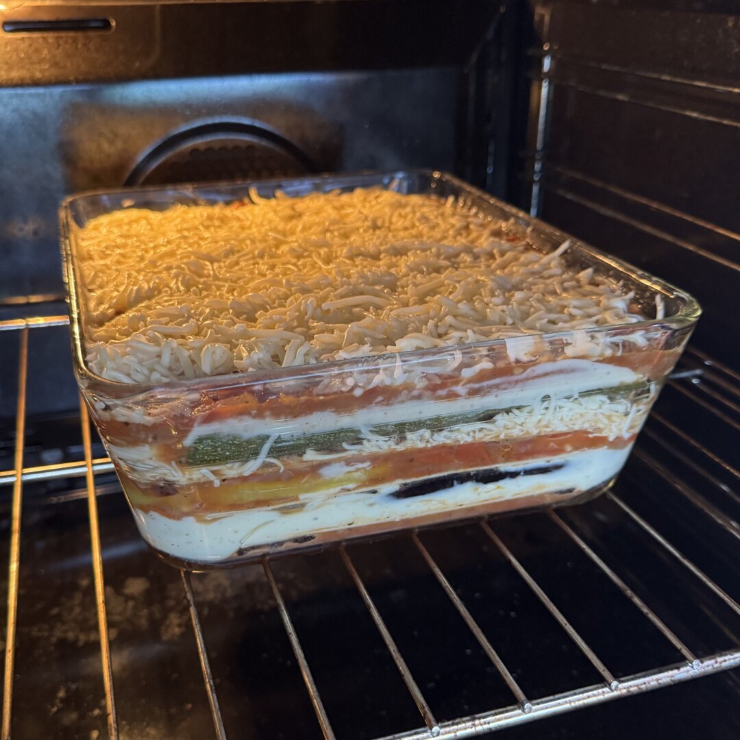 Big dish of lasagna in the oven. It has layers of red sauce, grilled vegetables, cheese sauce, and cheese.