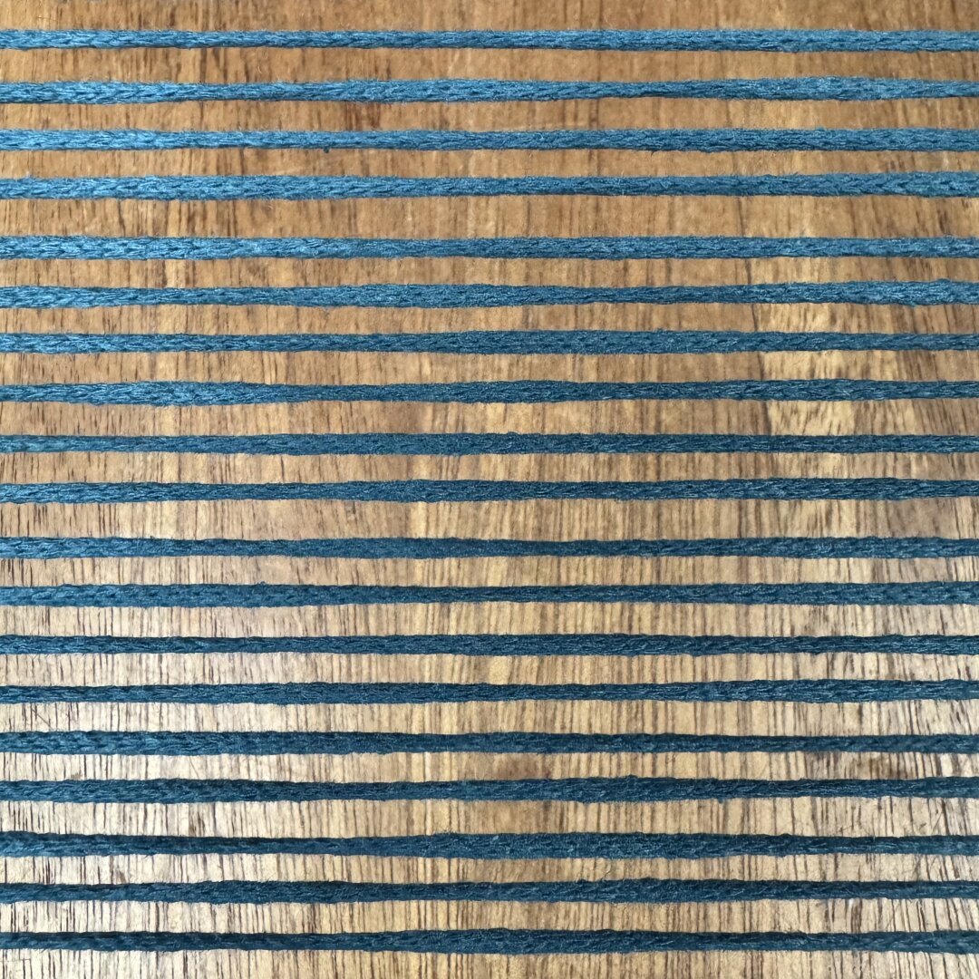 Horizontal blue threads above a wooden table.