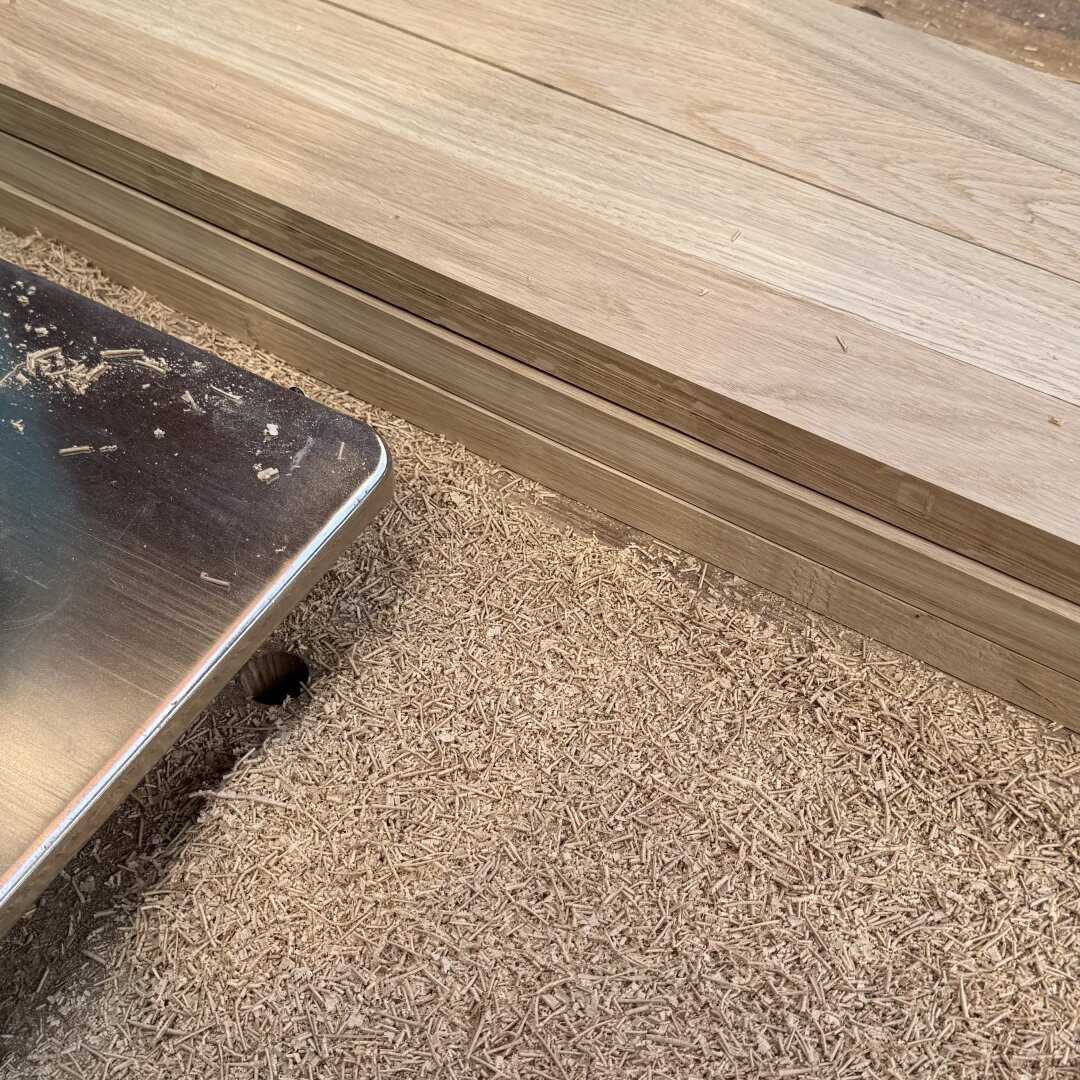 A part of the metal planer sole, sawdust, and planed wood.