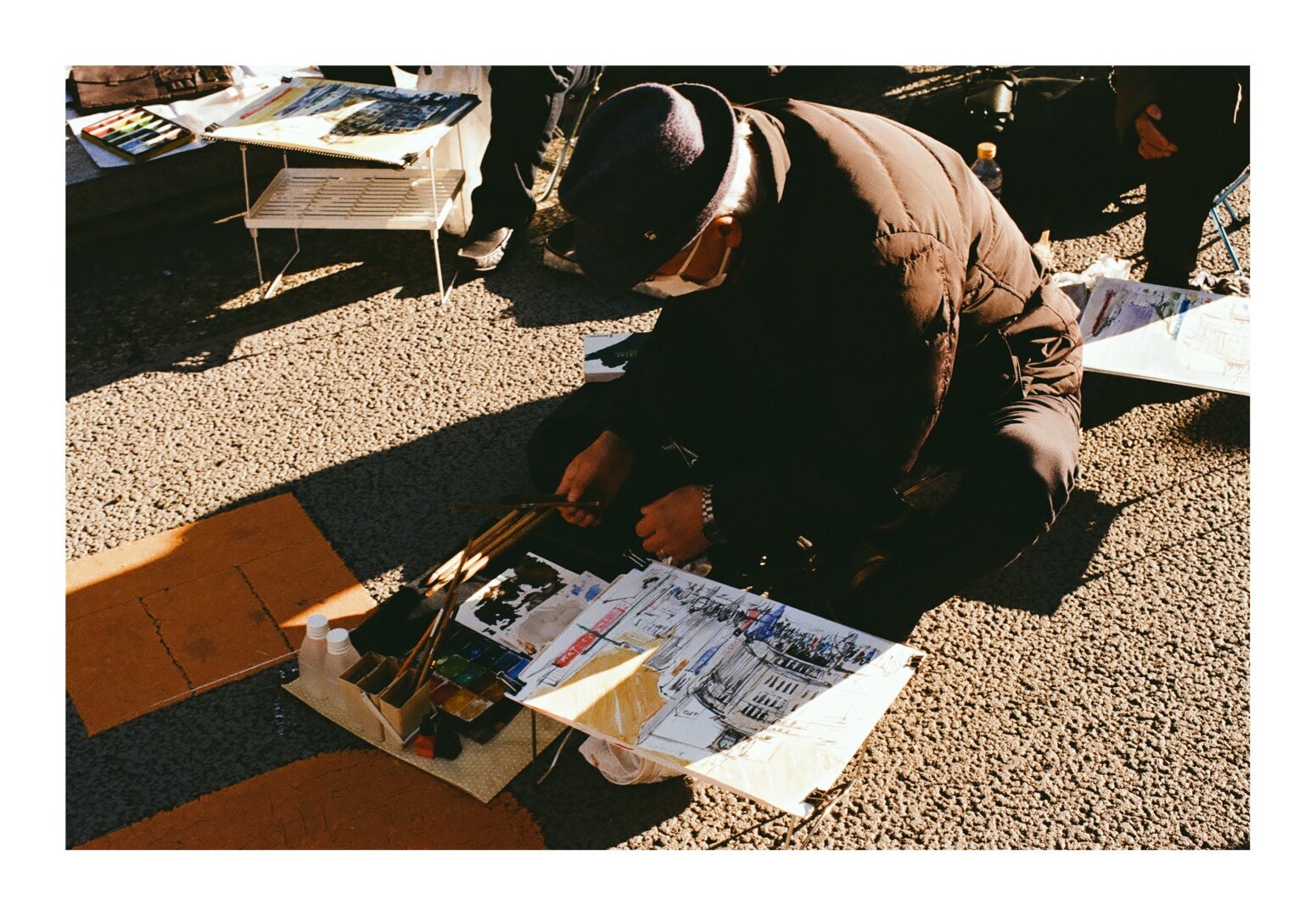 A man on the street painting a watercolor of the famous Seiko clock tower in Tokyo