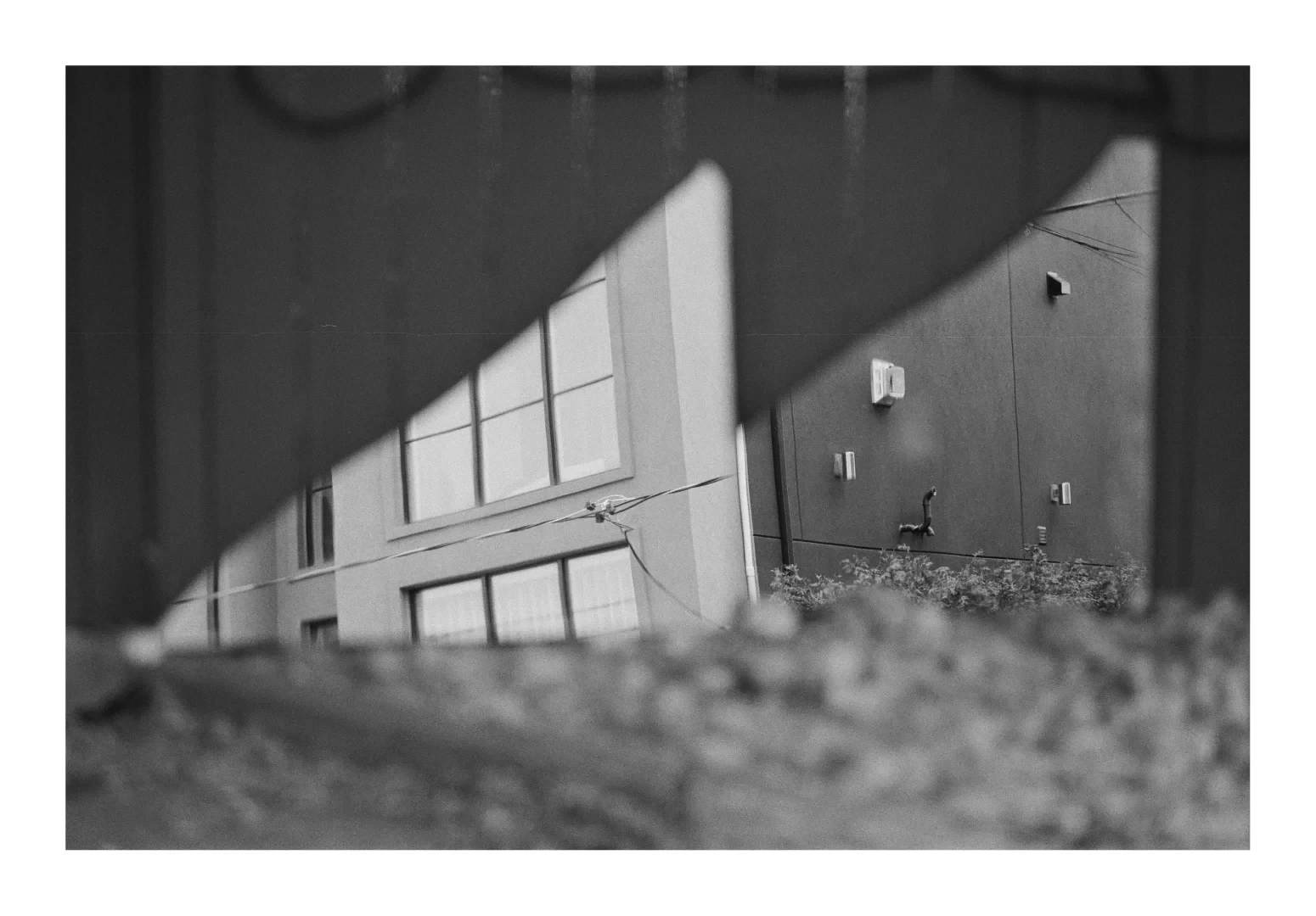 A black and white photograph of two broken shards of mirror that form right angled triangles. A home is reflected in the fragments.