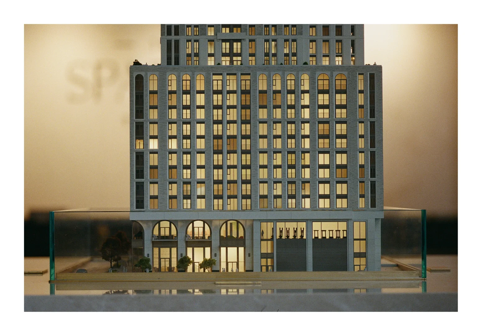 A colour photograph of an architectural model of a condominium building in the sales office. The scene is suffused with a with light within the building model.