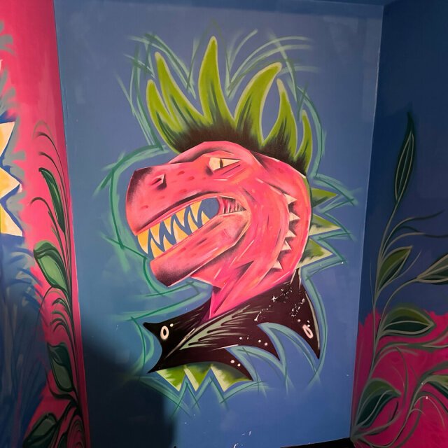A mural of a dinosaur with a green mohawk