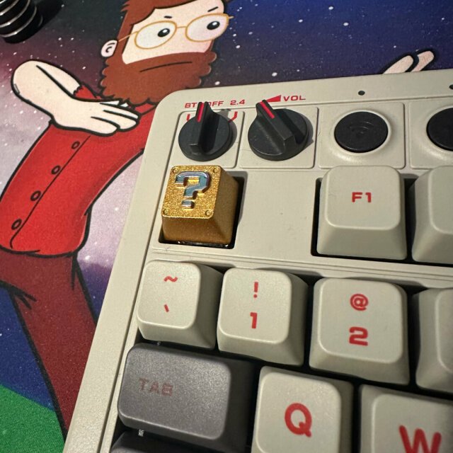 A gold Mario question mark key cap on a keyboard.
