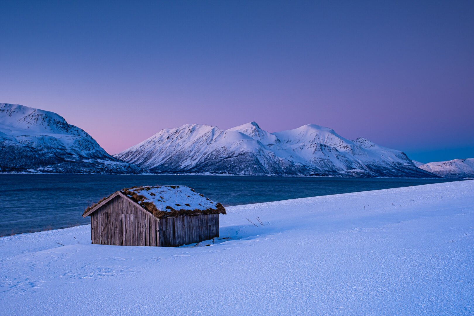 Einsame Holzhütte am winterlichen Fjord