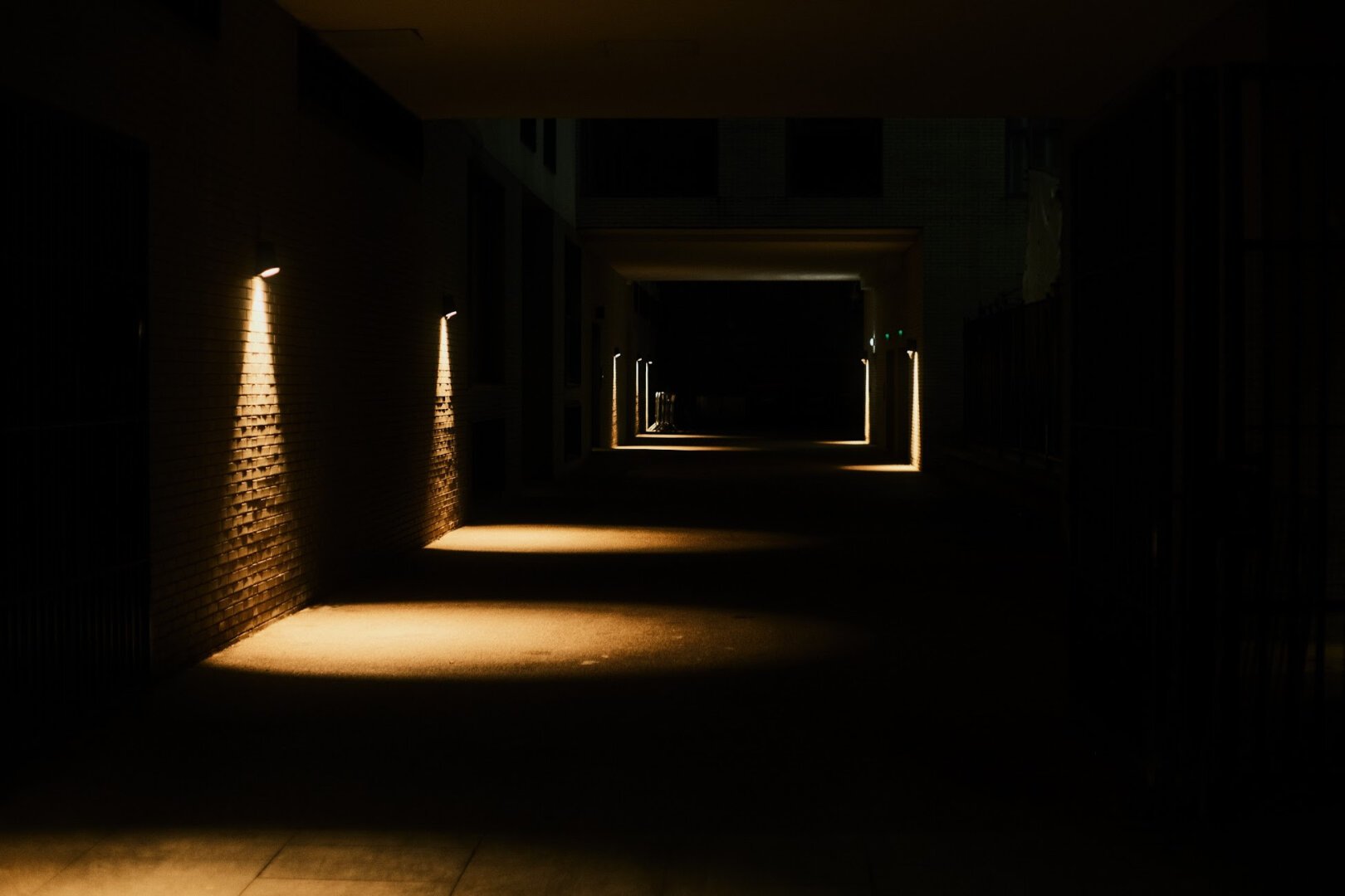 Dark corridor with wall lights on the side.