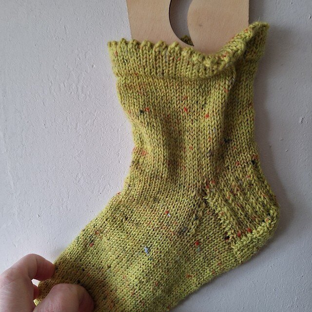 Neon green socks with speckles held against a wall