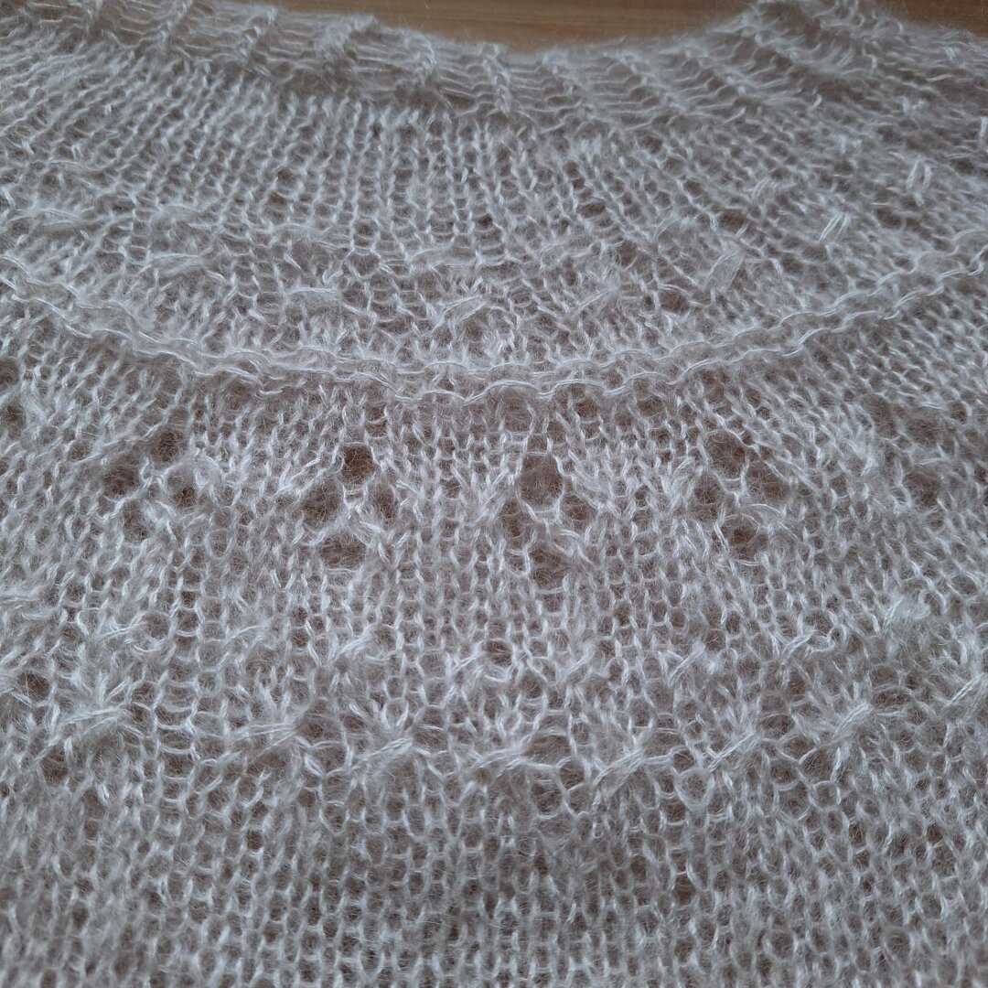 A close-up of a knitted ranunculus sweater in off-white mohair
