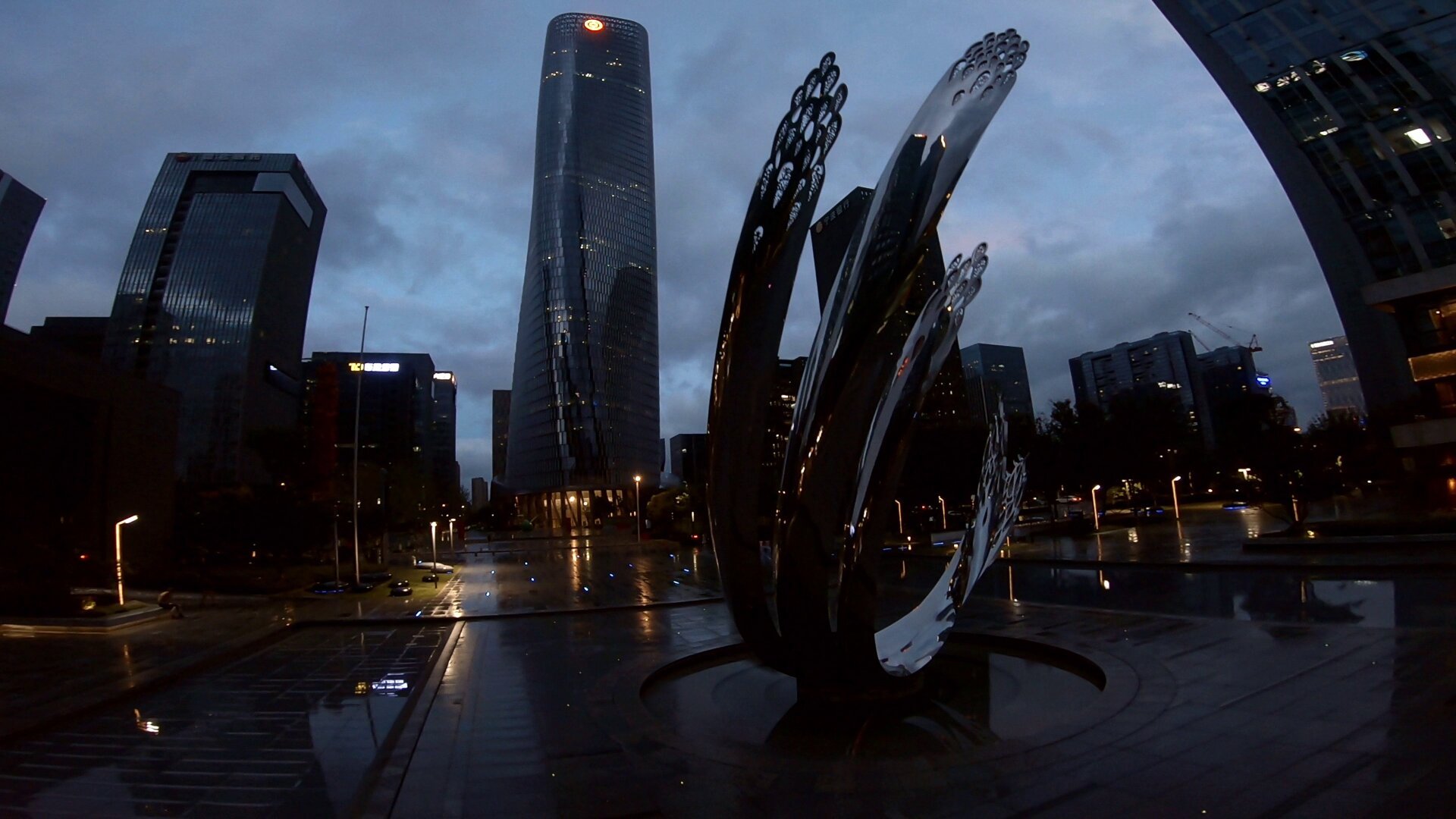 A shiny piece of urban sculpture in a dusk cityscape