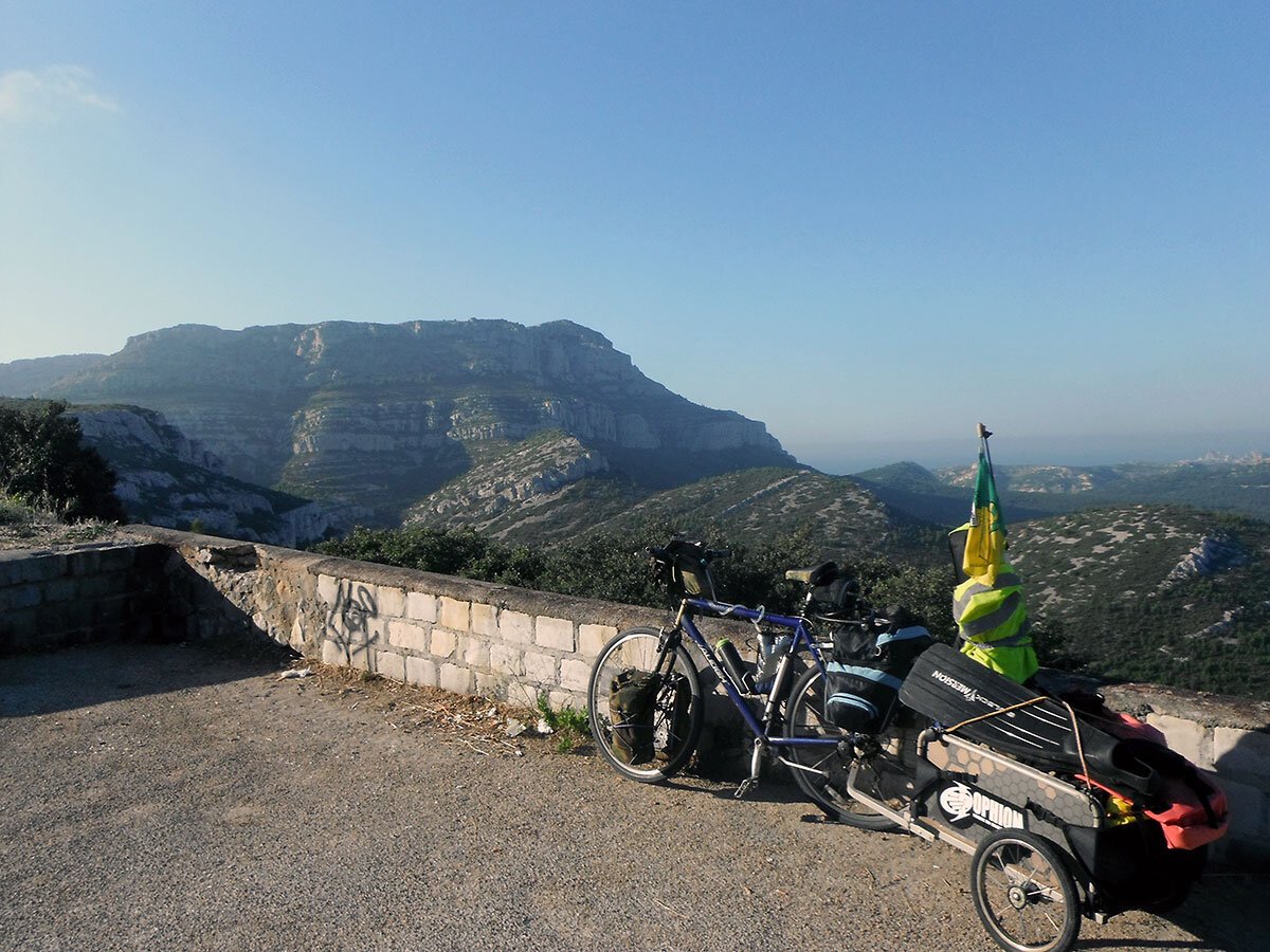 An overloaded bike with a trailer attached parked at a nice view in France.