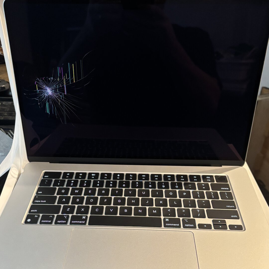 A silver MacBook Air with a broken LCD screen on the left side.