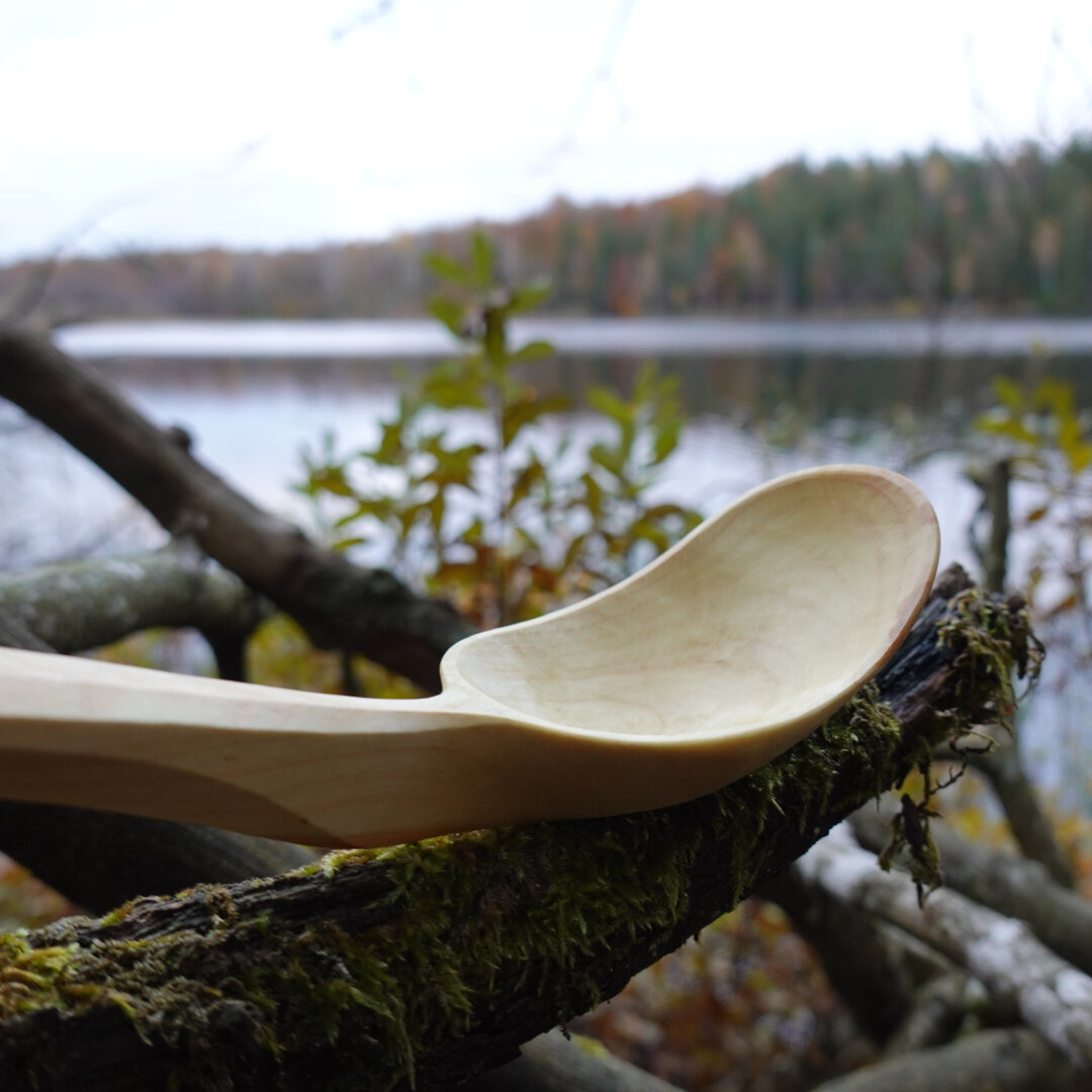 Wooden spoon bowl zoom in with water and forest background