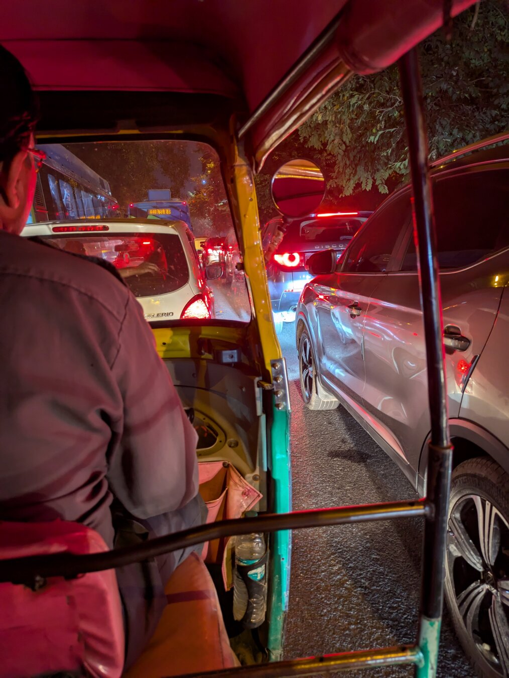 In the back of a tuktuk at nighttime with cars all around