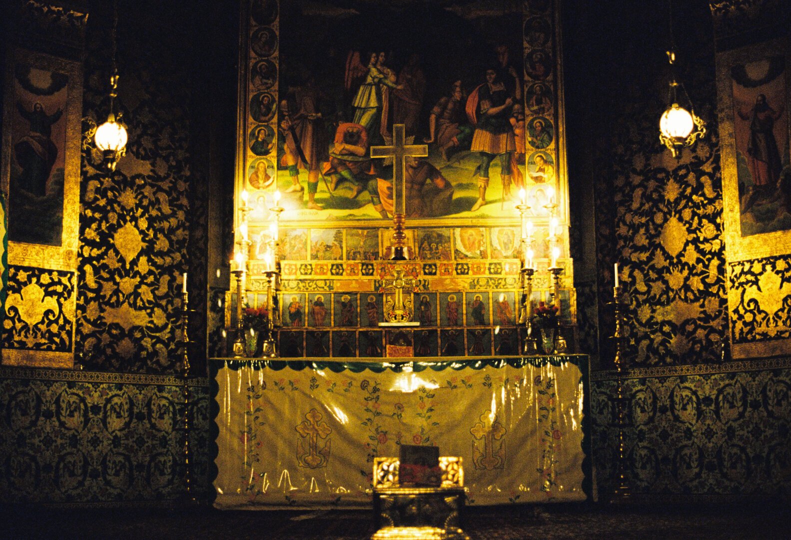 The image shows the altar of Vank Cathedral, decorated with gold, colorful artwork, and lit by candlelight.