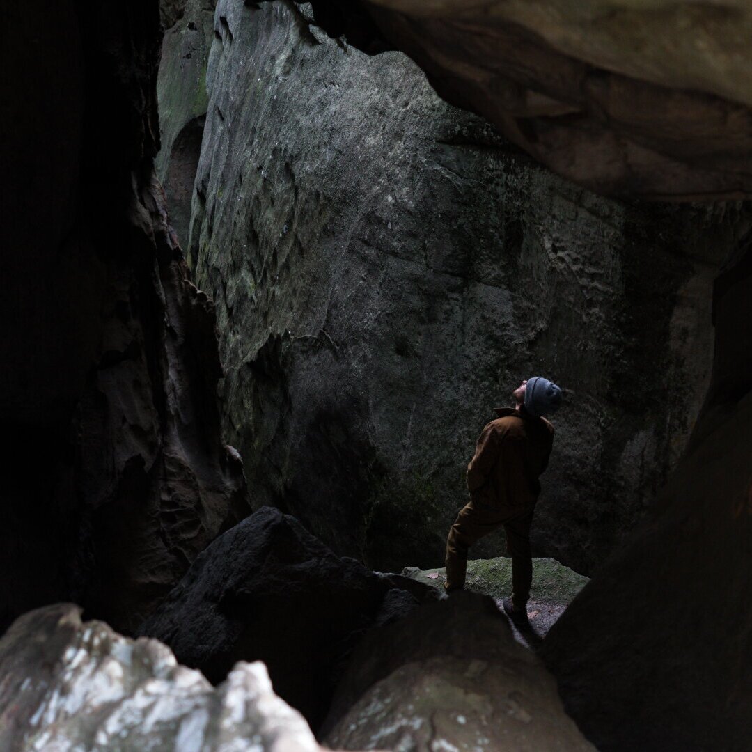 A person, contently smiling to themselves, seen through the rearview mirror of a car