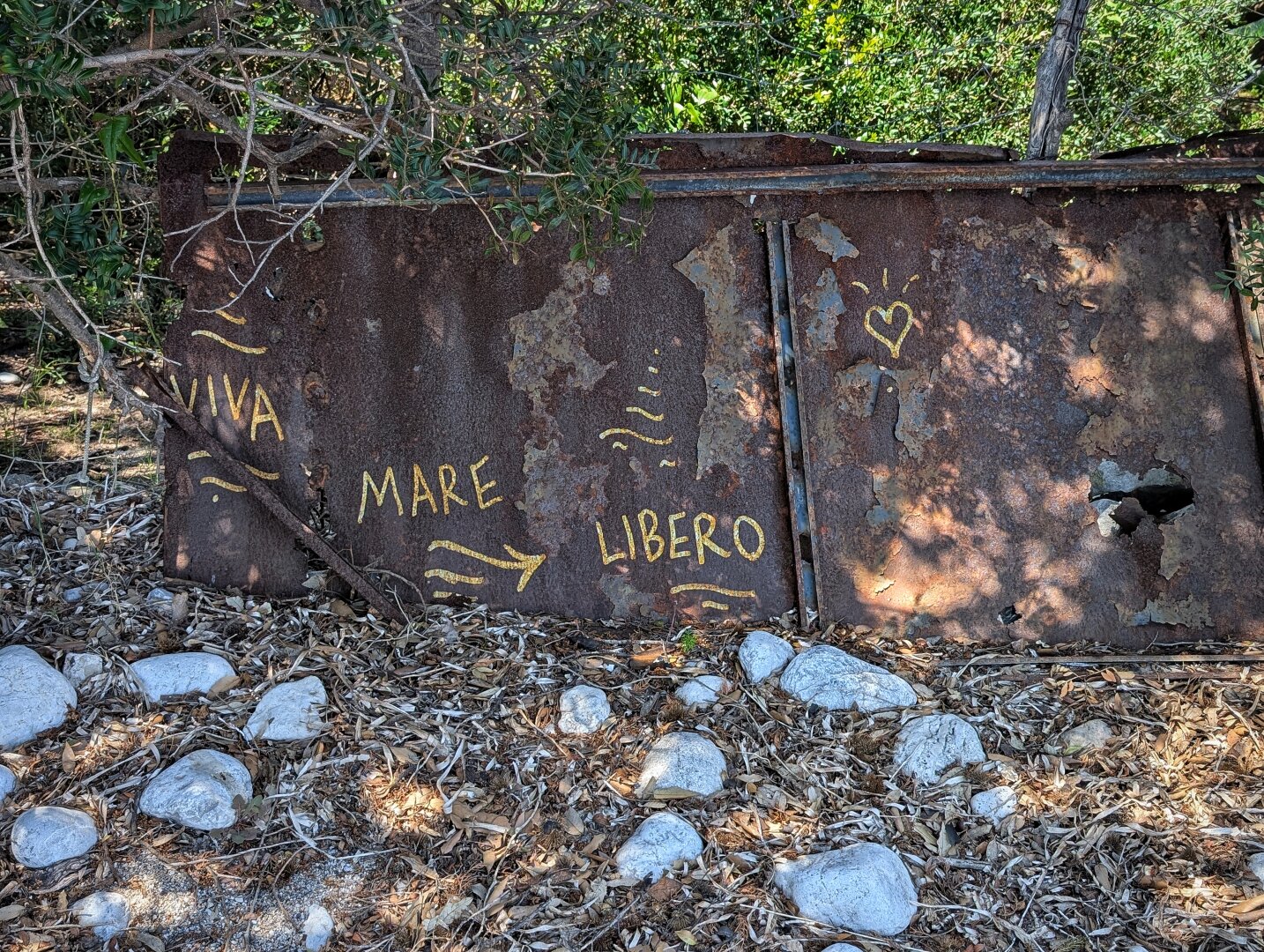 Rusty sheet metal with "Viva mare libero" ("Long live free sea") written on it.