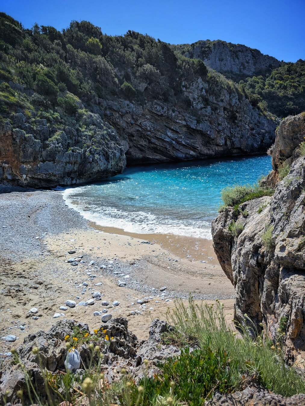 Sea washing over the white pebble seashore seen from a rock.