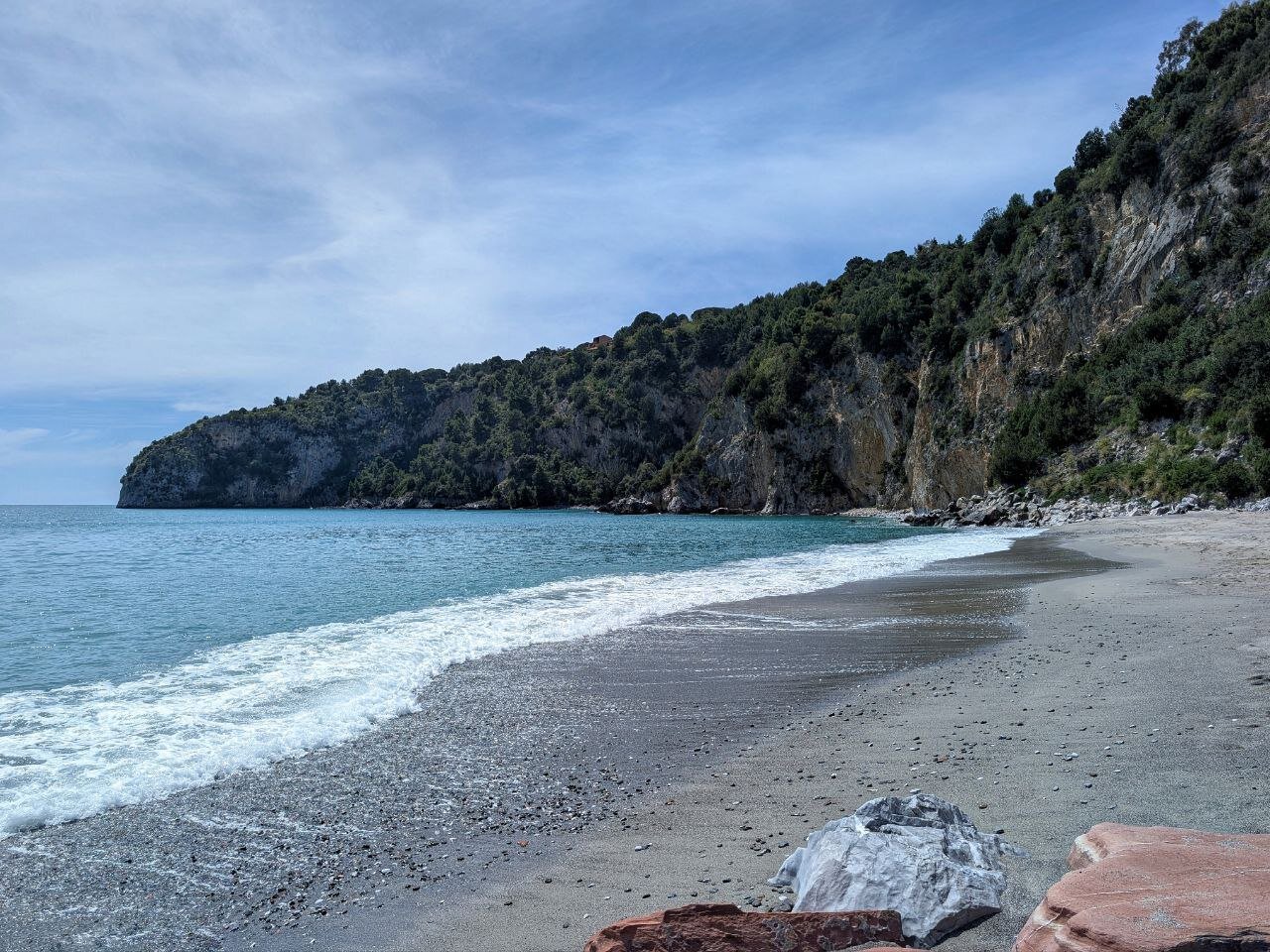 The waves of the sea crash onto the sand of the Buon Dormire beach, which is sheltered by the rocks.