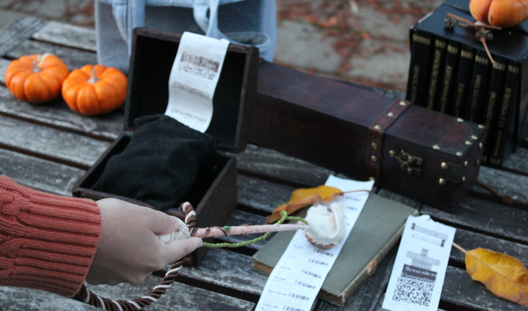 A person's arm using a wand to select a bar code from a piece of paper connected to a box that also prints paper.