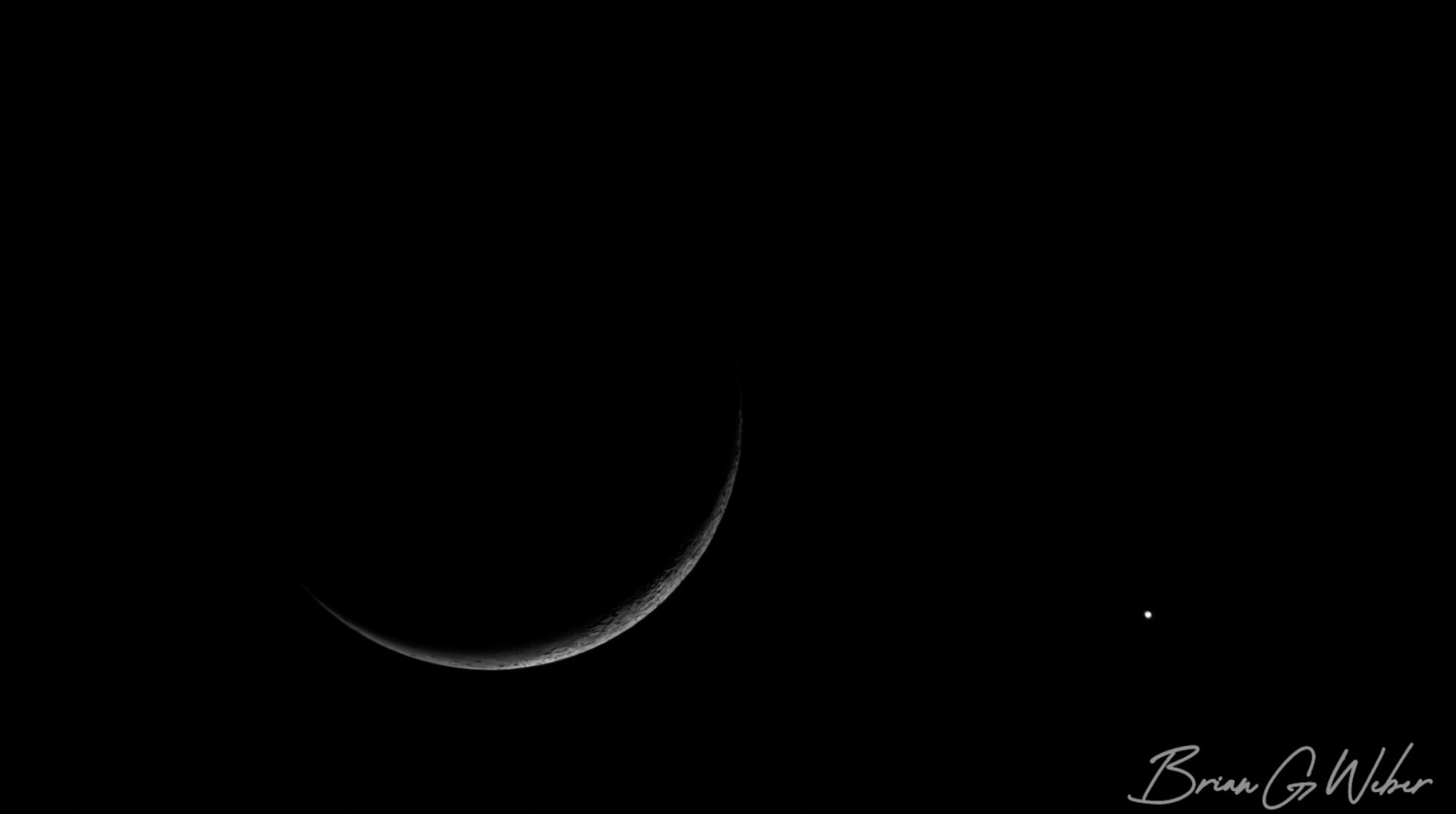 A tiny sliver of waning crescent moon with the bright dot of Venus off to its right