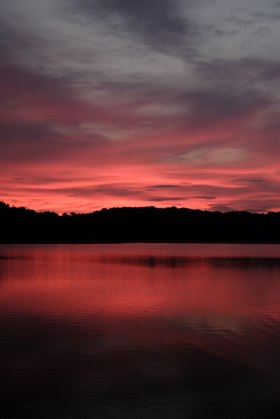 A very dark red sky over a lake at dawn