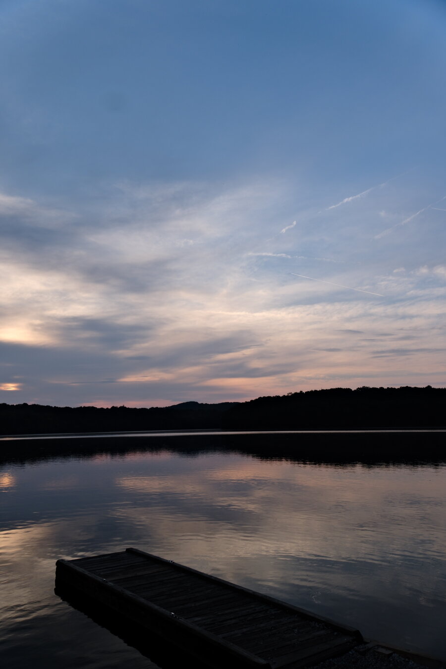Blue sky and white clouds over a lake after the sun rose. Clouds are reflected on the water.